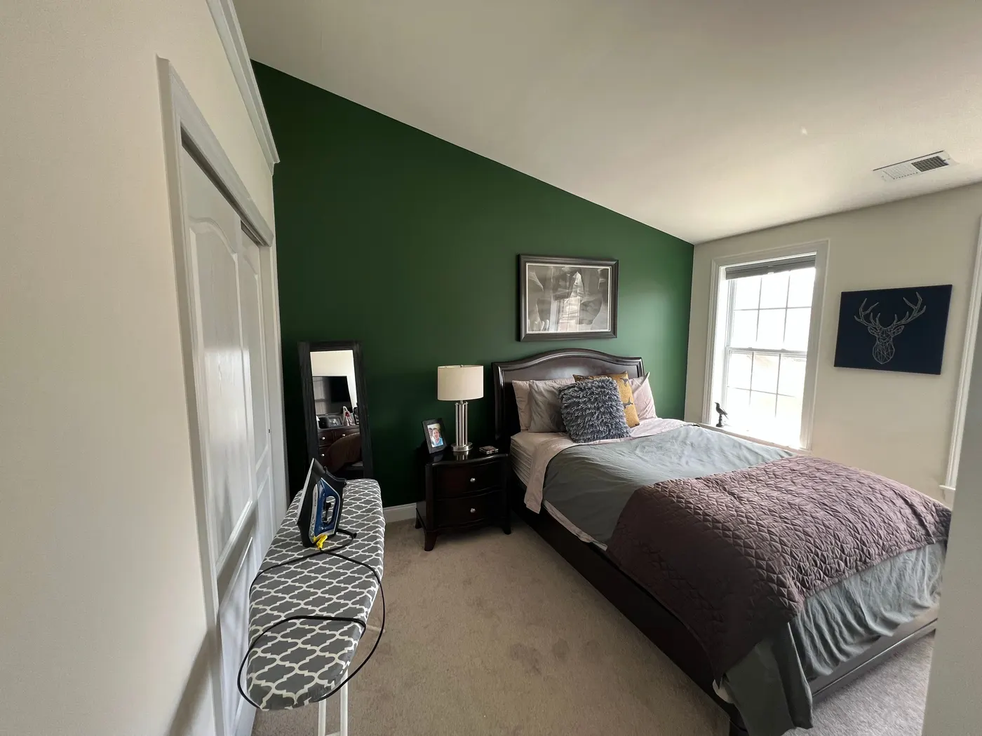 Bedroom with a deep green accent wall behind the bed, the other walls and trim white