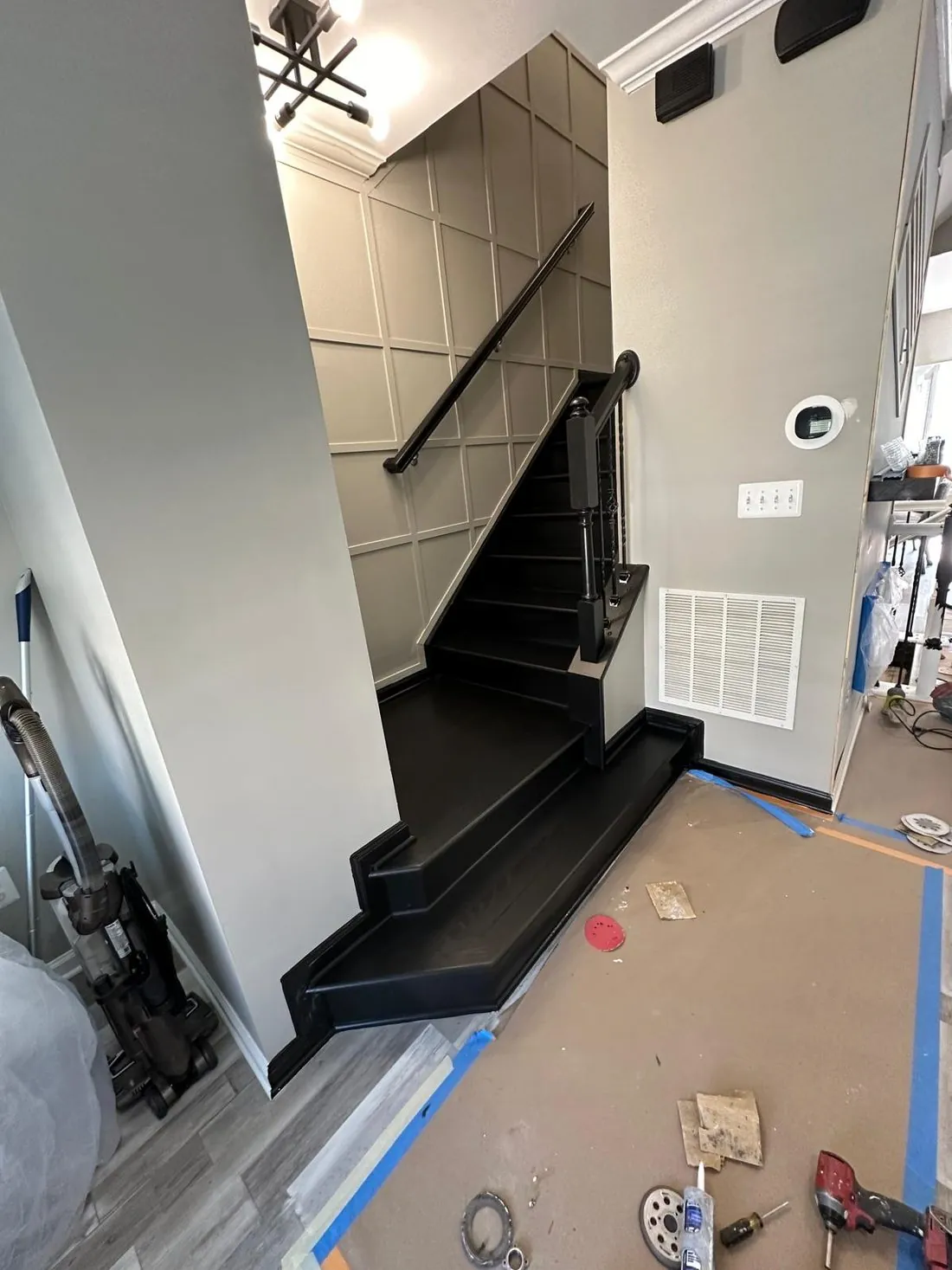 The same stairwell after painting, the molding grid finished in warm greige with the stair treads and handrail in black