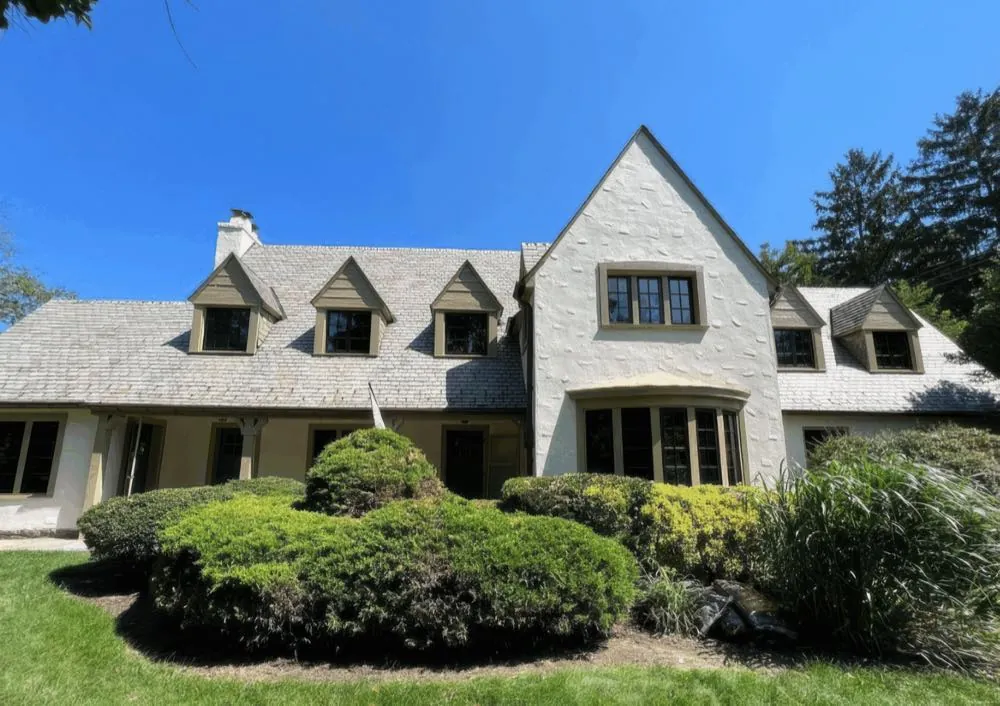 Full front elevation of a stucco home with four dormers after an exterior repaint by Rise and Prime Painting